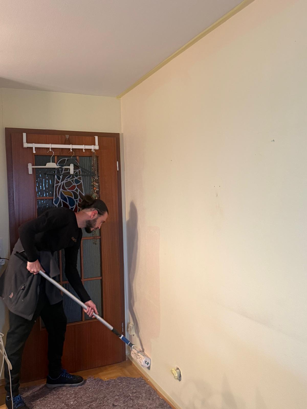 Mitarbeiter streicht Wand mit Rolle